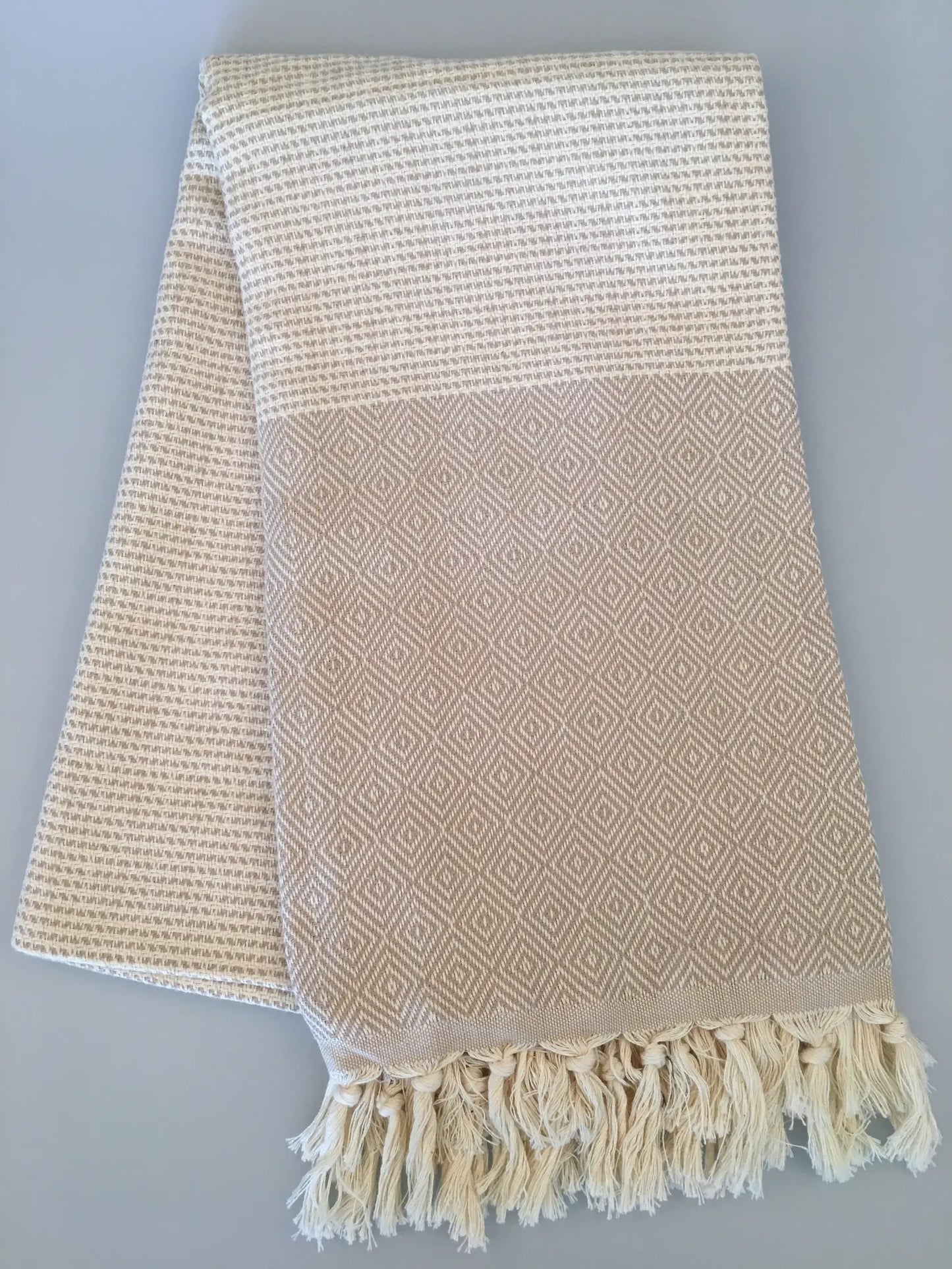 "Lycia Patara Turkish towel in beige with diamond pattern and fringed ends, folded on a light gray background."