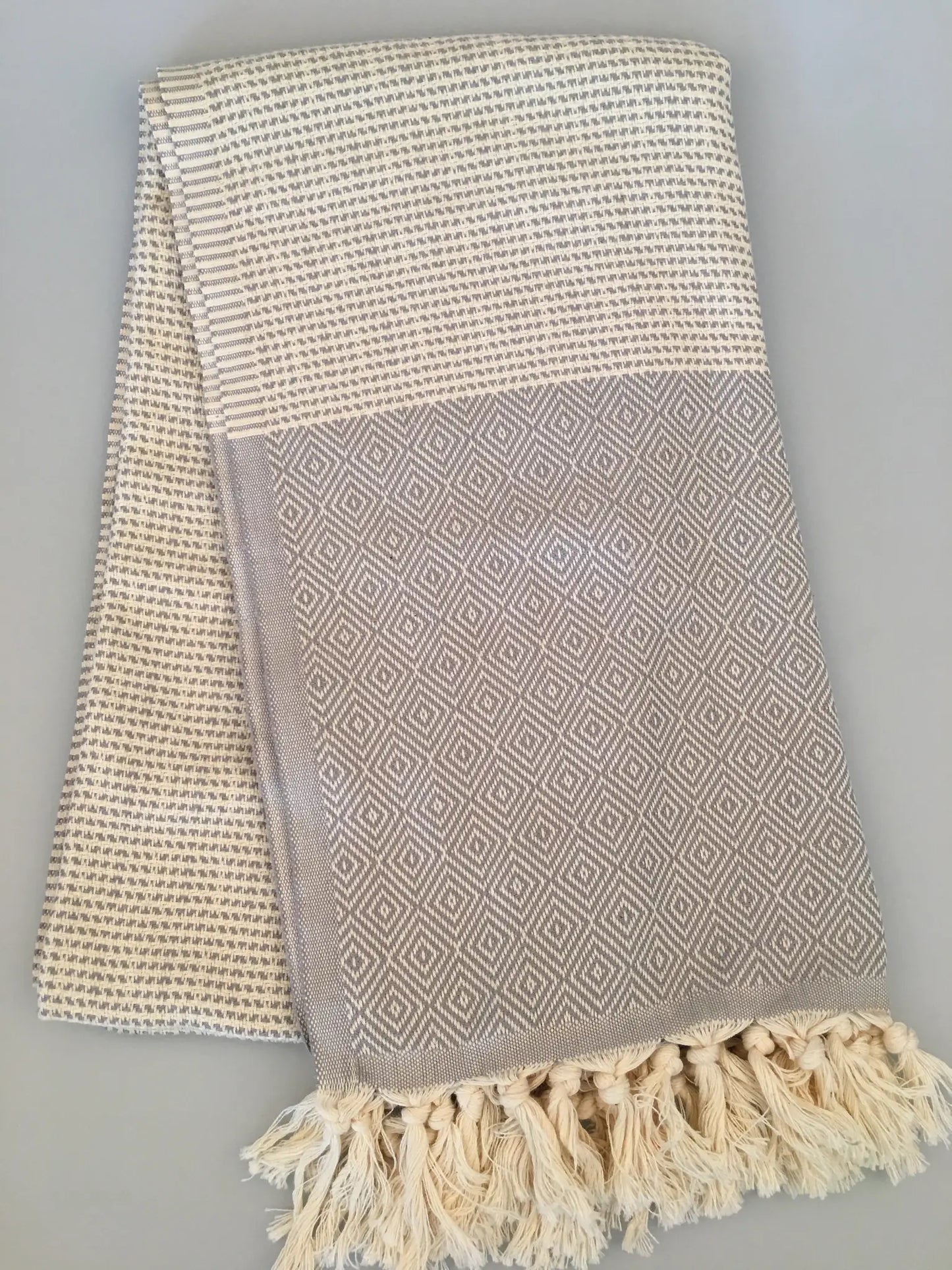 "Light gray Turkish towel with diamond pattern and cream woven texture, finished with fringed edges."