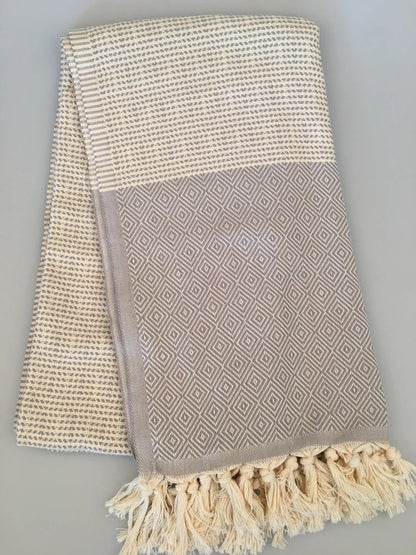 "Light gray Turkish towel with diamond pattern and cream woven texture, finished with fringed edges."