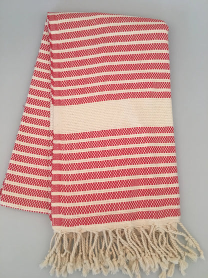 Red and white striped Hittite Turkish towel with fringed edges, laid flat on a gray background.