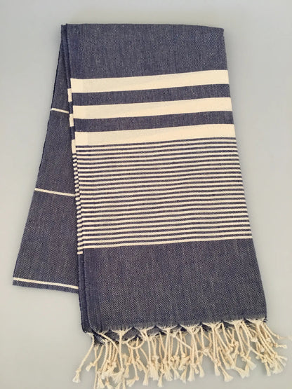"Navy blue Turkish towel with cream stripes and fringe edges, folded with a textured weave pattern."